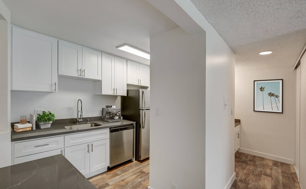 an empty kitchen with white cabinets and a stainless steel refrigerator