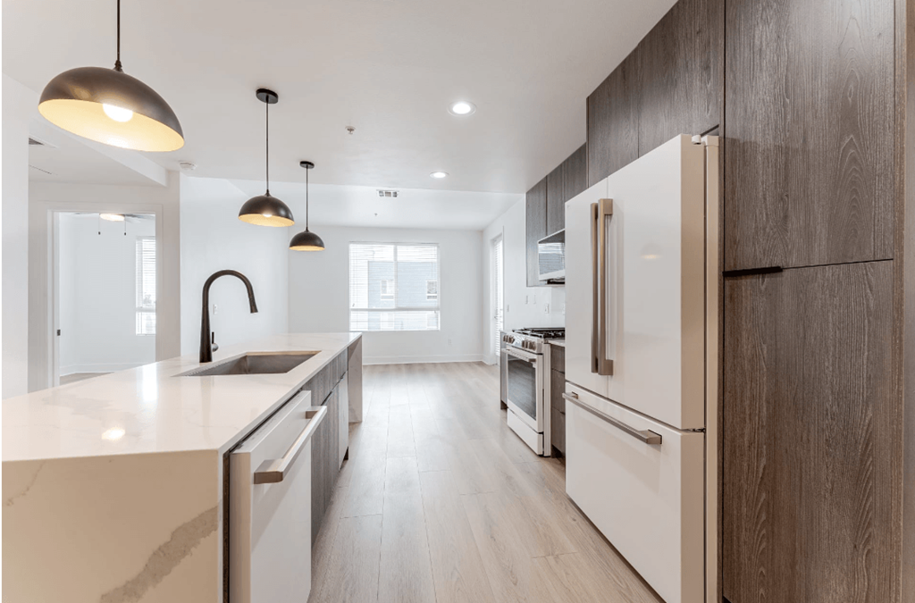 A modern kitchen with a white countertop and wooden cabinets.