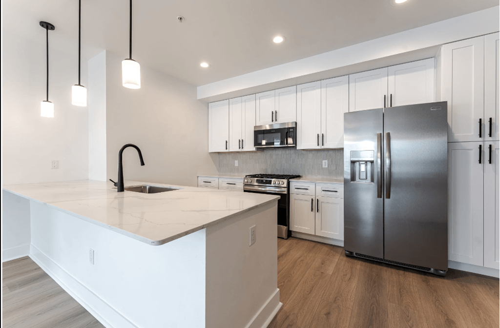 A modern kitchen with a white countertop and stainless steel appliances.