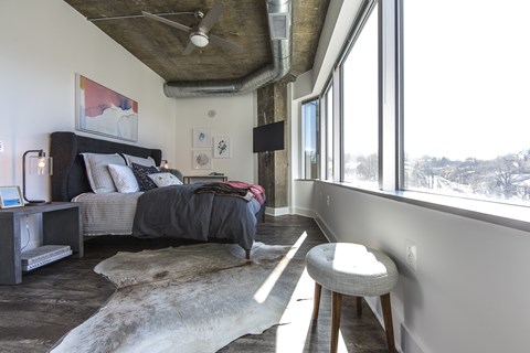 A bedroom with a bed, a chair, and a rug.