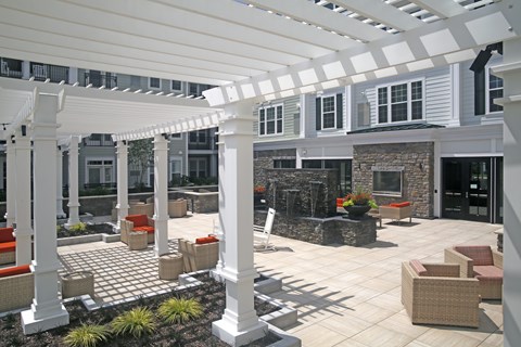 A patio with a white pergola and wicker furniture.