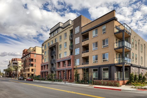 a view of a building on a city street with a cloudy sky in the background