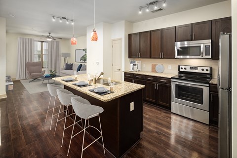 A modern kitchen with dark wood cabinets and stainless steel appliances.