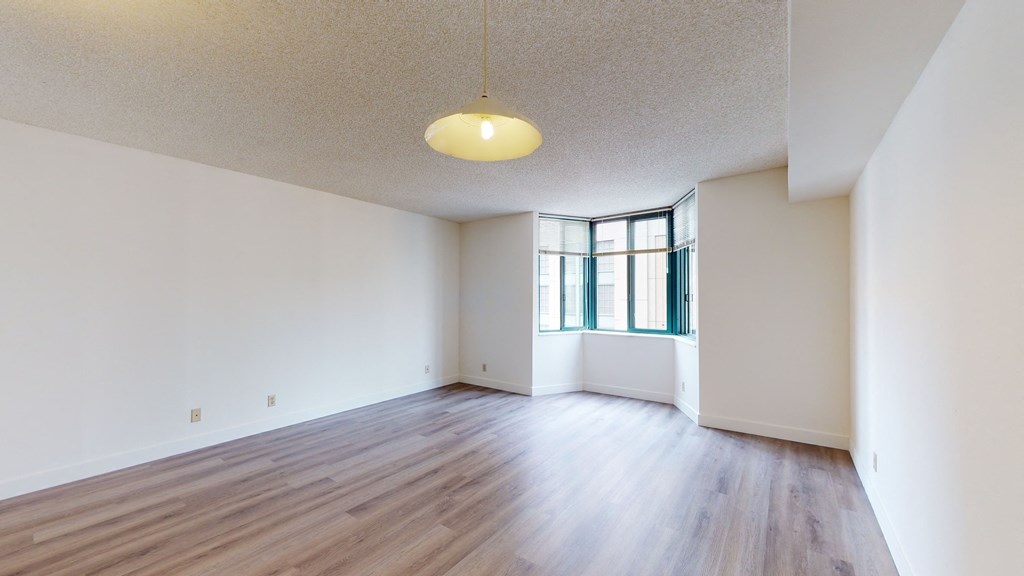 an empty living room with hardwood floors and a large window