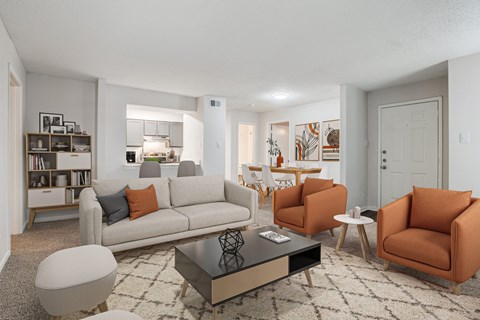 A living room with a grey couch, orange chairs, and a coffee table.