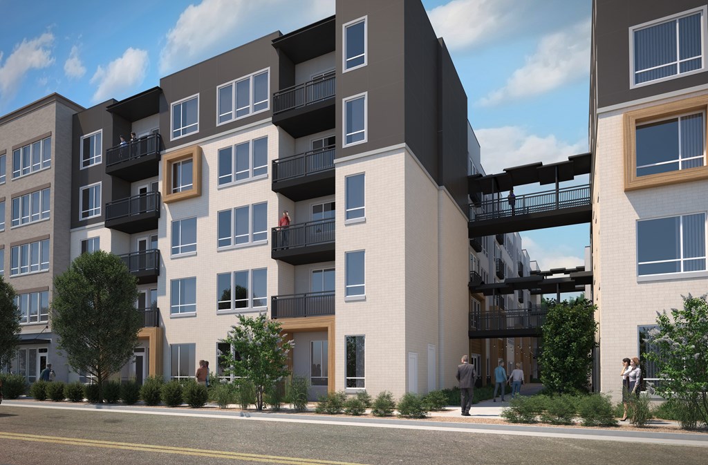 A modern apartment building with balconies and a pedestrian bridge.