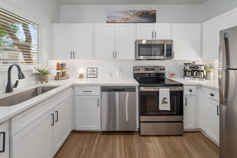A modern kitchen with white cabinets and stainless steel appliances.
