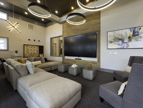 A modern living room with a large couch, a television, and a painting on the wall.