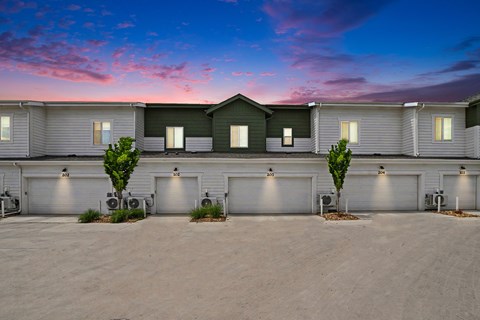 A row of houses with garages and trees in front.