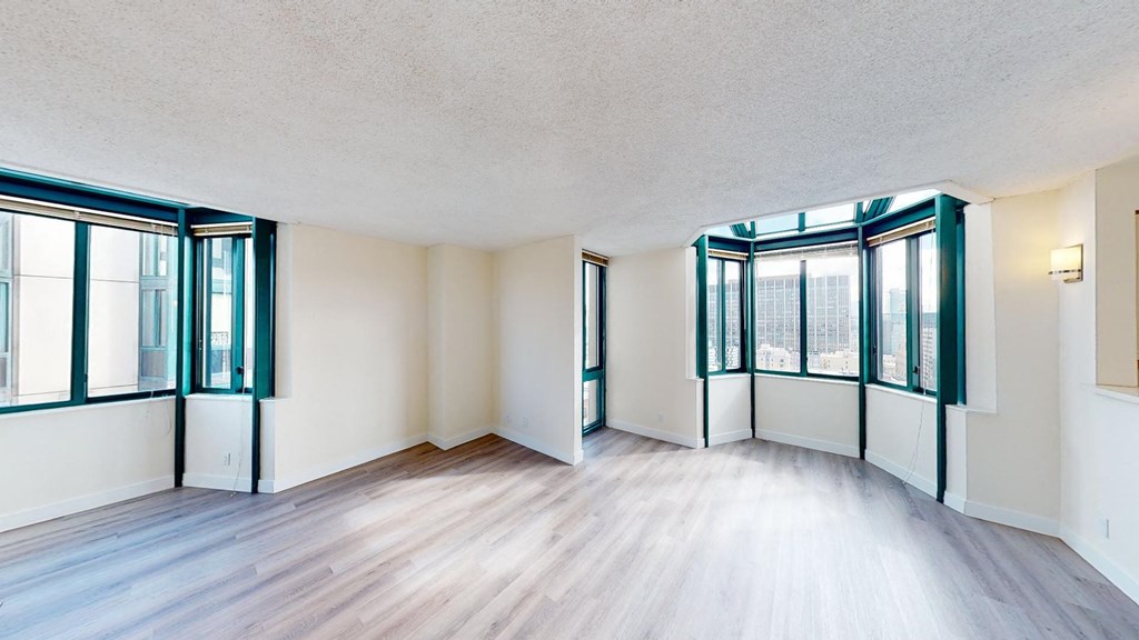 an empty living room with hardwood floors and large windows