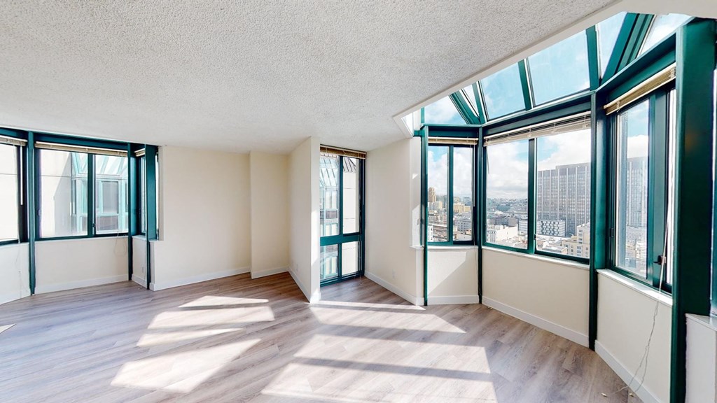 an empty living room with large windows and hardwood floors