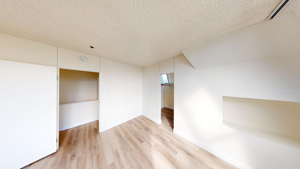 a bedroom with white walls and hardwood floors
