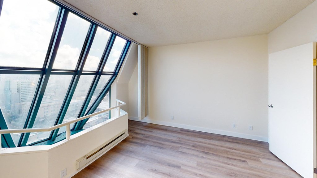 an empty room with a large window and hardwood floors