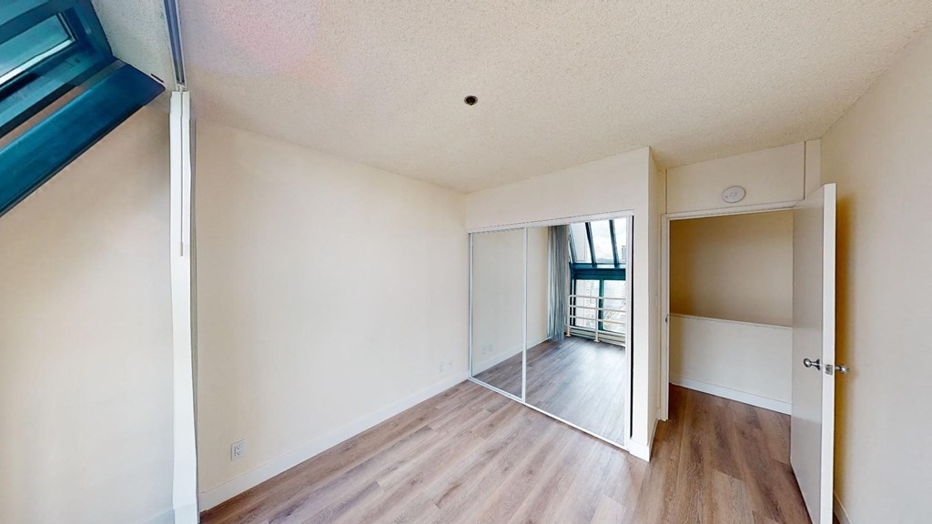 a bedroom with hardwood floors and white walls