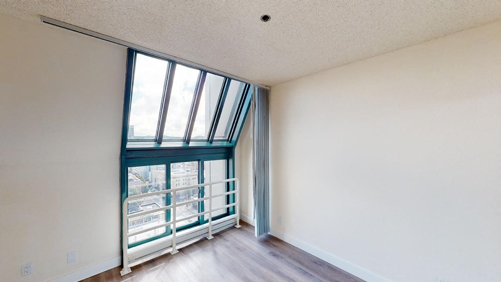 an empty room with white walls and a balcony with a view of the city