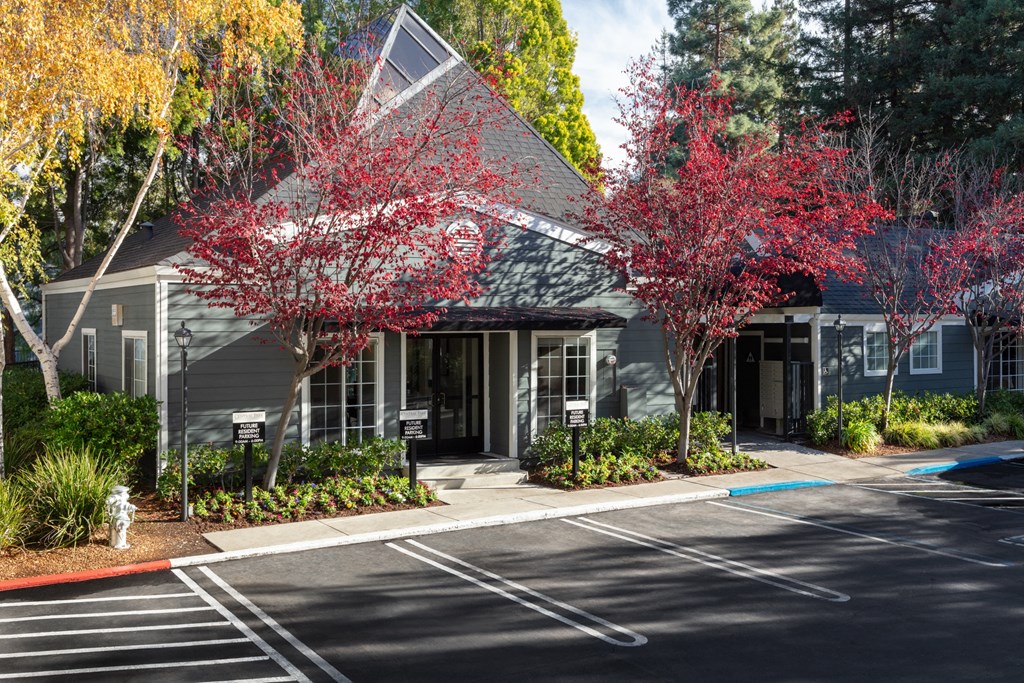 a gray building with a gray roof with trees with red leaves in front of it