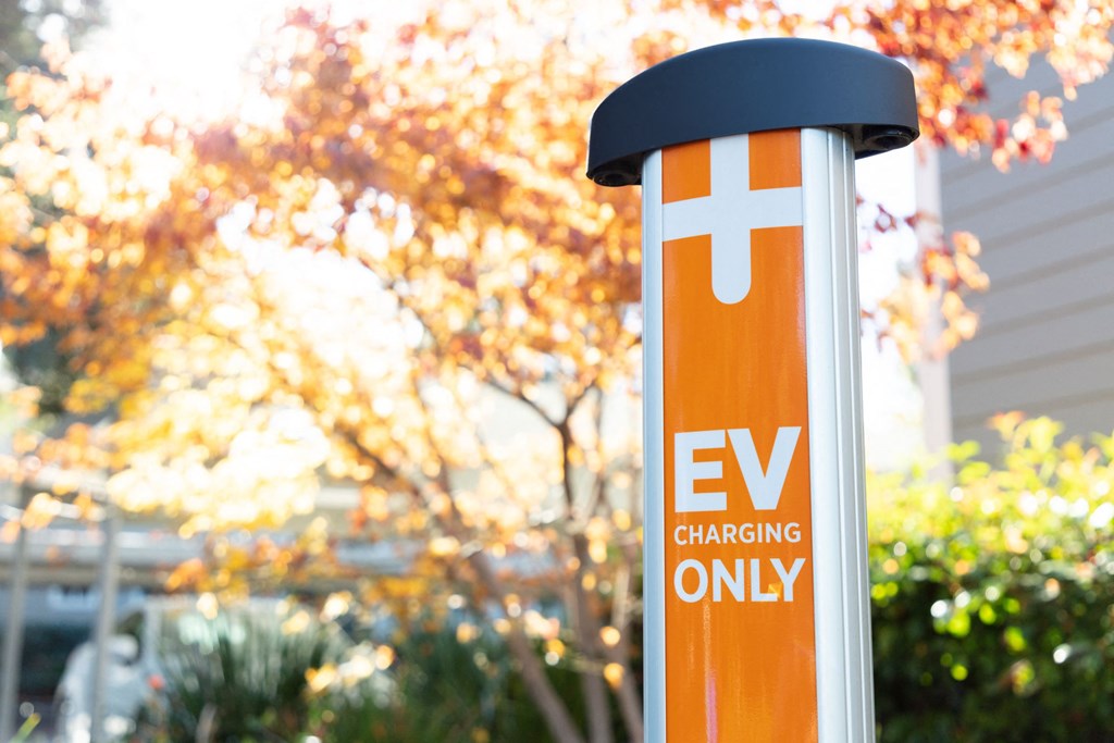 an ev charging station in front of a house with trees in the background