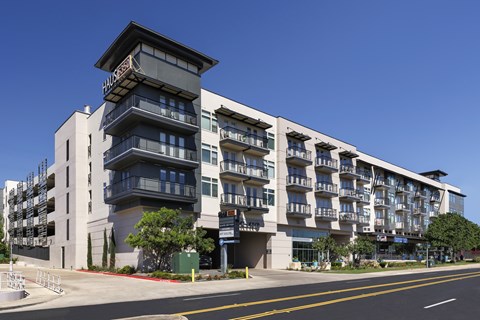 A modern multi-story building with a sign that reads "Halston" on the top floor.