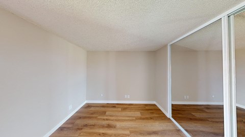 a bedroom with a large mirror and hardwood flooring