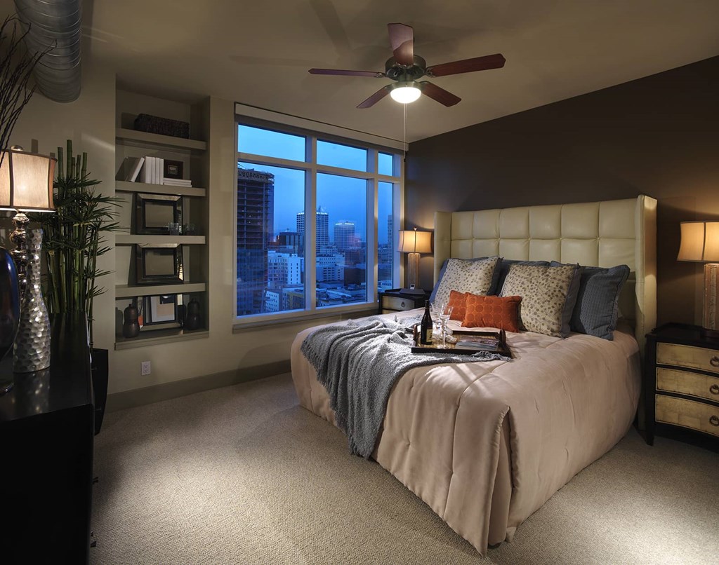 A bedroom with a large bed and a window overlooking the city.