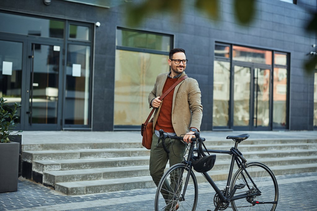 a man walking his bike down the street