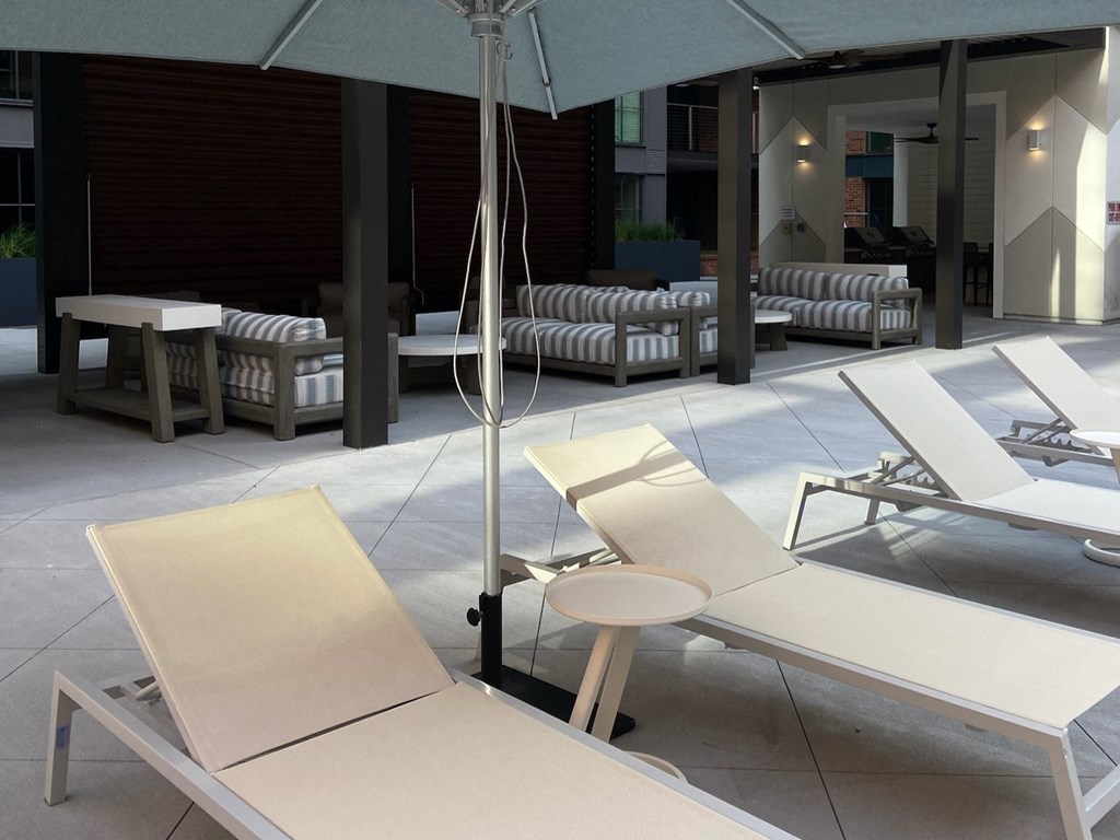 a group of white lounge chairs on a patio with an umbrella