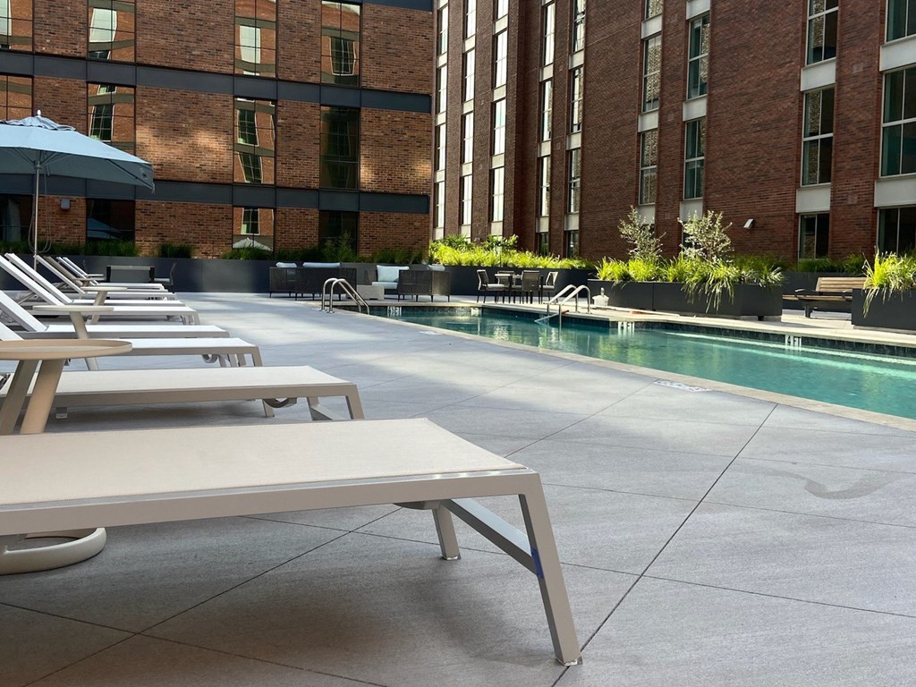a row of white tables and chairs next to a swimming pool