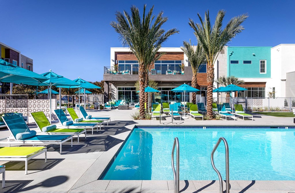 A pool area with sun loungers and palm trees.