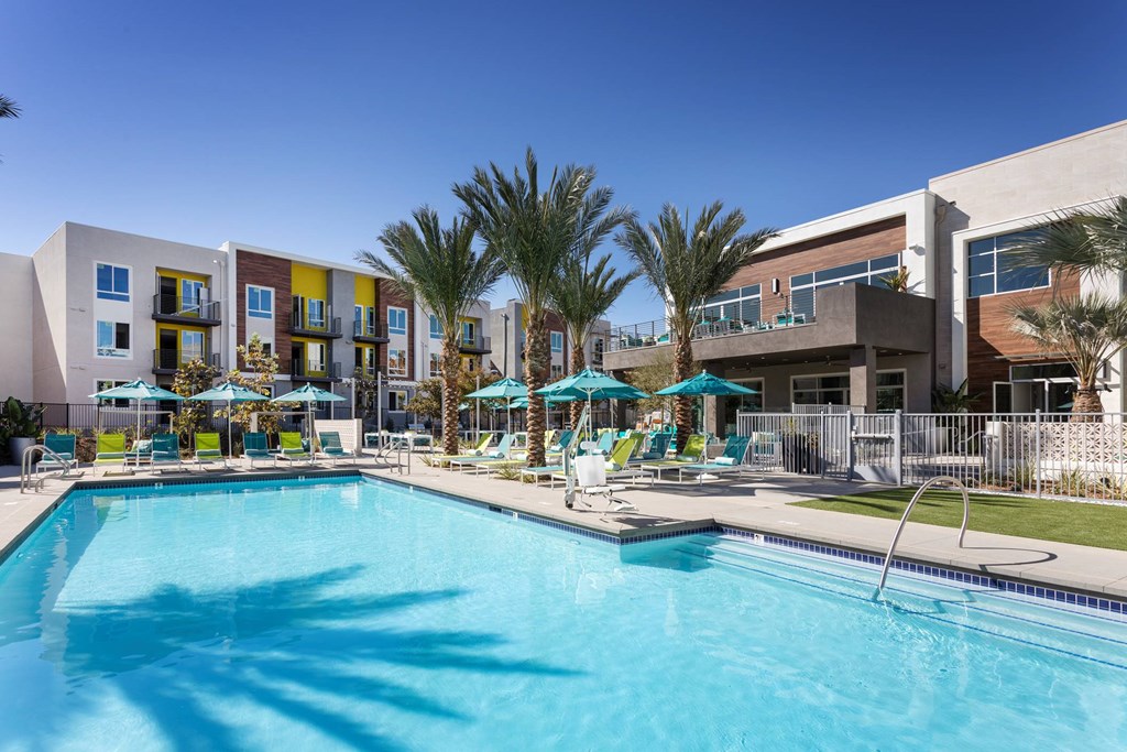 A swimming pool surrounded by palm trees and umbrellas.