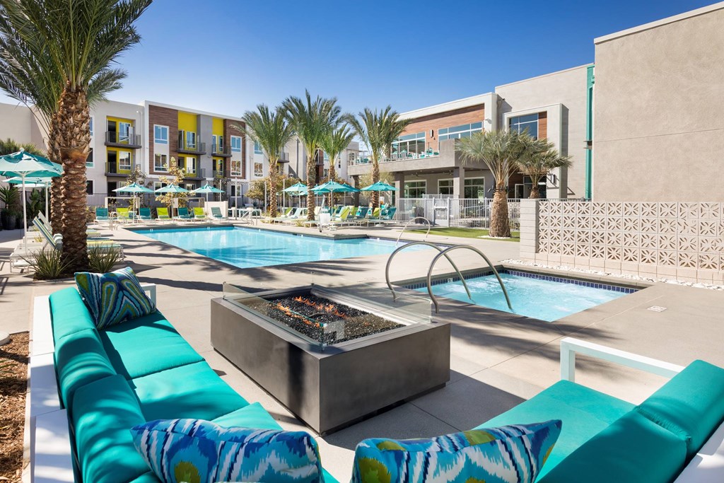 A pool area with a fire pit and lounge chairs.