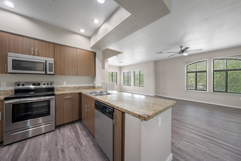 an empty kitchen with stainless steel appliances and a granite counter top