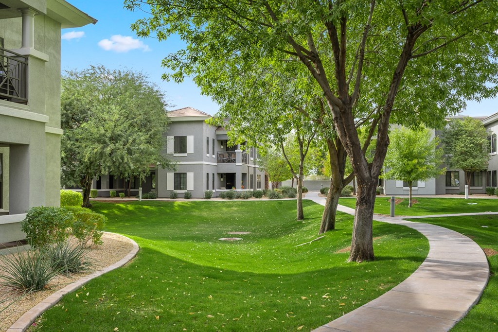 a walkway through the grass in front of an apartment building