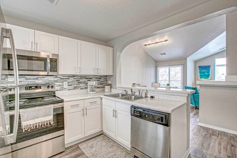 A modern kitchen with white cabinets and stainless steel appliances.
