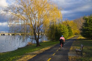 a man riding a bike down a path next to a lake