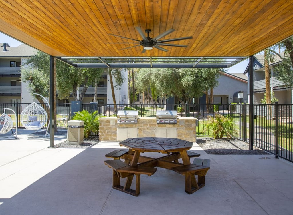 a patio with a picnic table and a grill