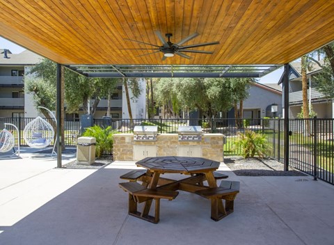 a patio with a picnic table and a grill