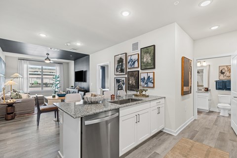 A modern kitchen with a large island and a living room area with a couch and a chair.