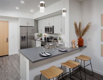 model kitchen with a large island with two stools and a stainless steel refrigerator model kitchen with a large island with two stools and a stainless steel refrigerator