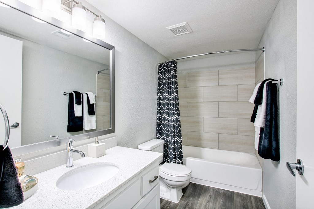 a bathroom with a white sink and toilet next to a white bathtub with a shower curtainat The Julia, Arizona