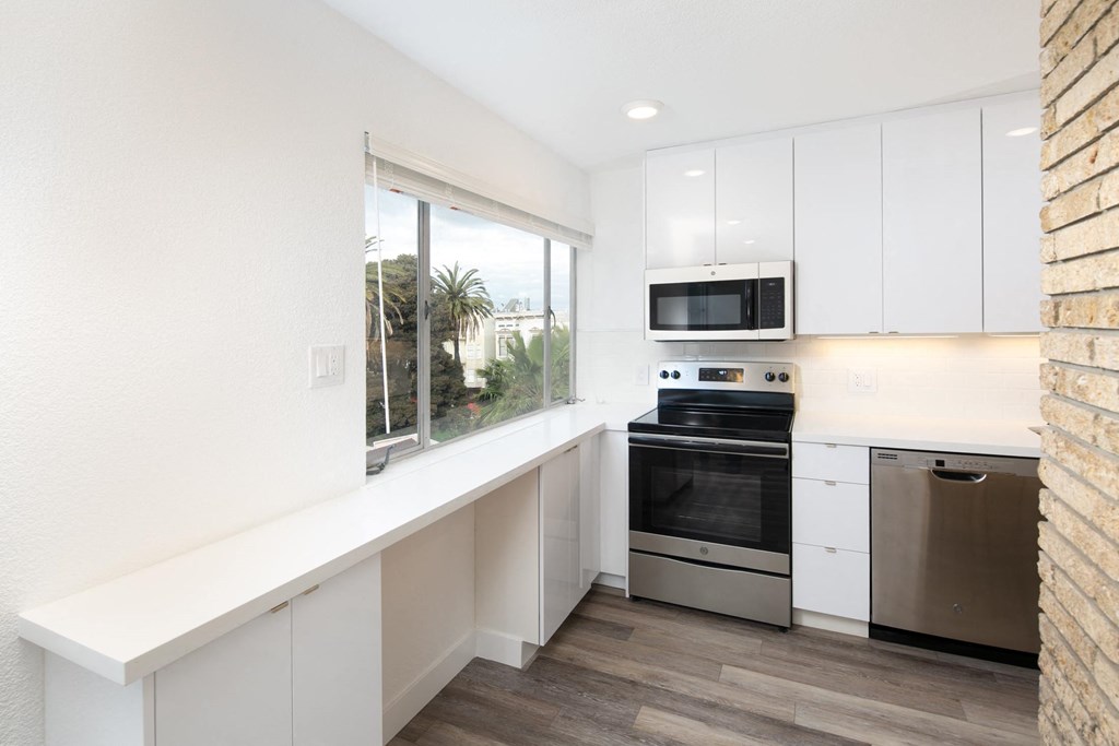 a kitchen with white cabinetry and a large window