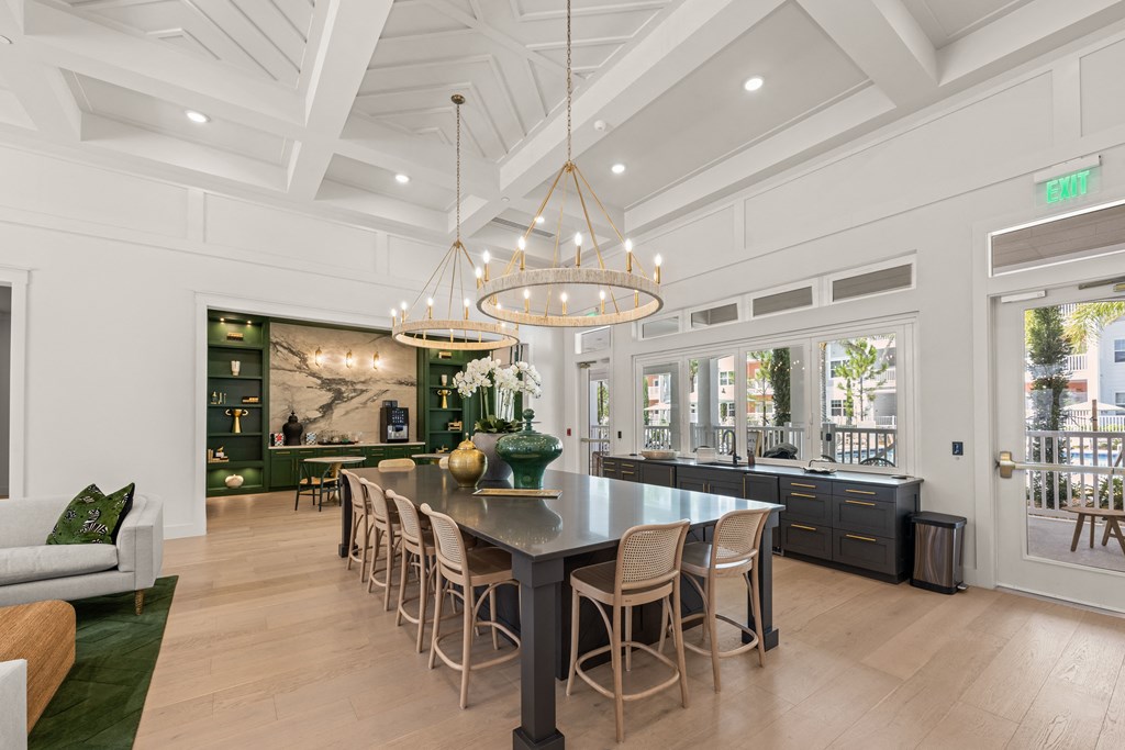 the kitchen has a large island with chairs and a chandelier
