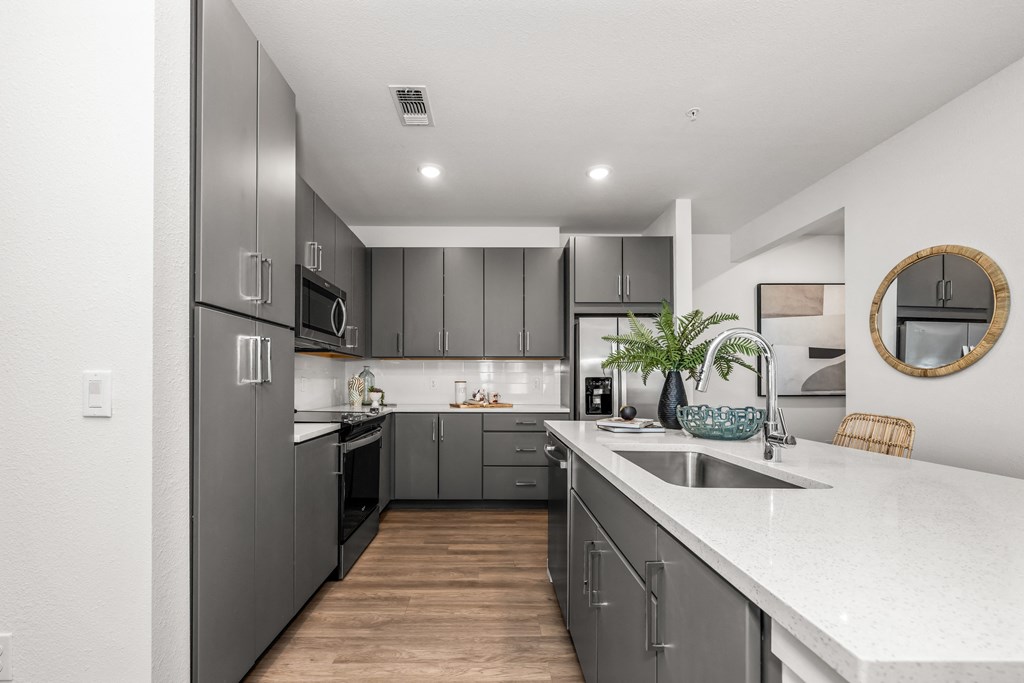 a kitchen with gray cabinets and white countertops and a sink