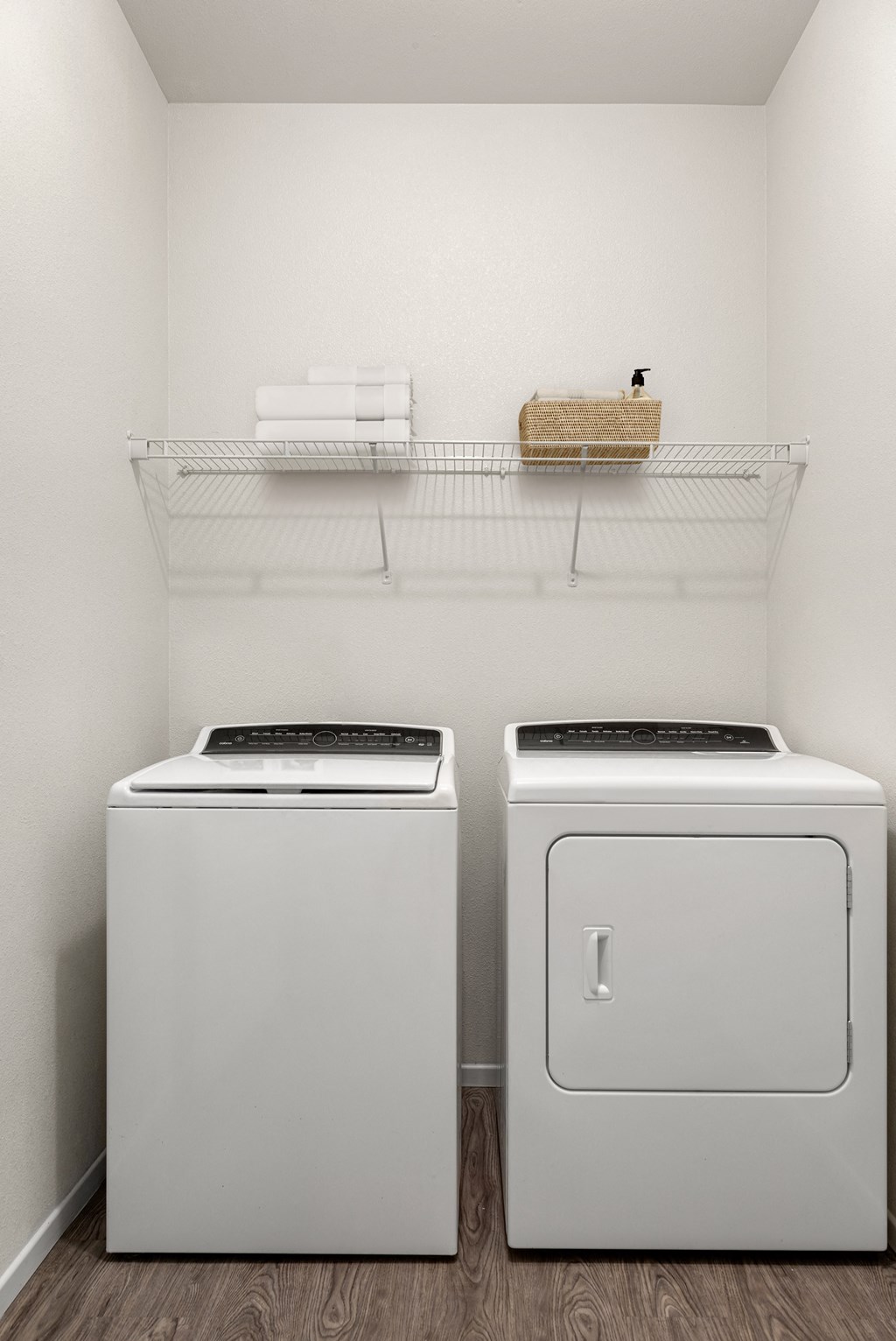 two washers and dryers in a white room with a shelf above them