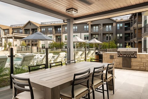 A patio with a table and chairs and umbrellas.