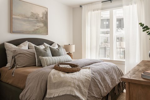 A bedroom with a large bed and a painting on the wall.