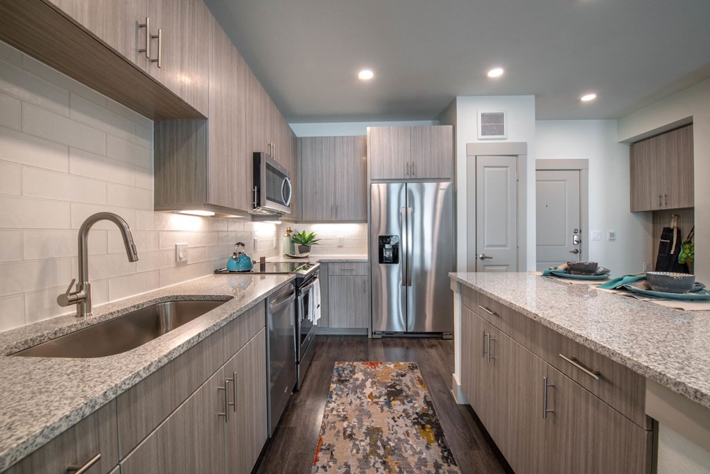 a kitchen with marble counter tops and a stainless steel refrigerator