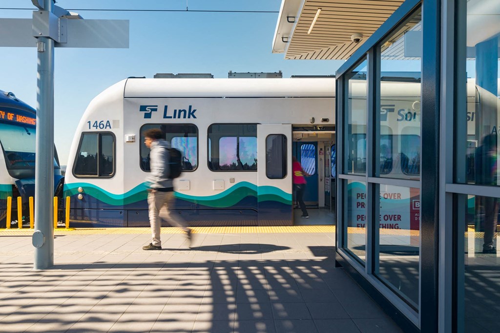 a man walking on a platform in front of a white and blue train at Ion Town Center, Shoreline Washington