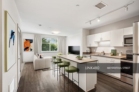 A modern kitchen with white cabinets and a dining area with a white sofa and chairs.