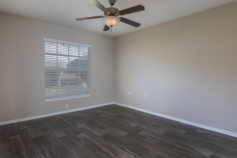 A room with a ceiling fan and wooden flooring.