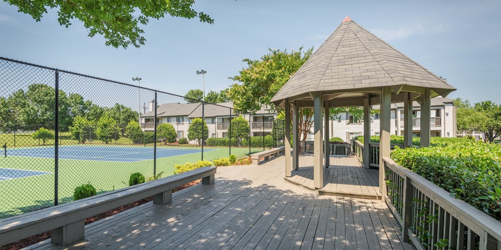 a gazebo with a tennis court in front of a house